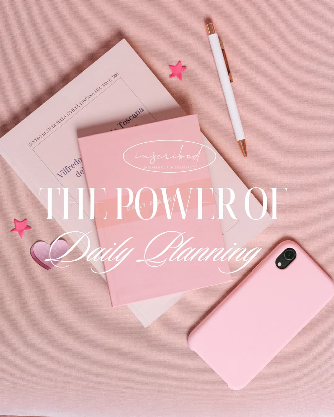 Pink daily planner, pen, and stationery arranged on a soft pink desk